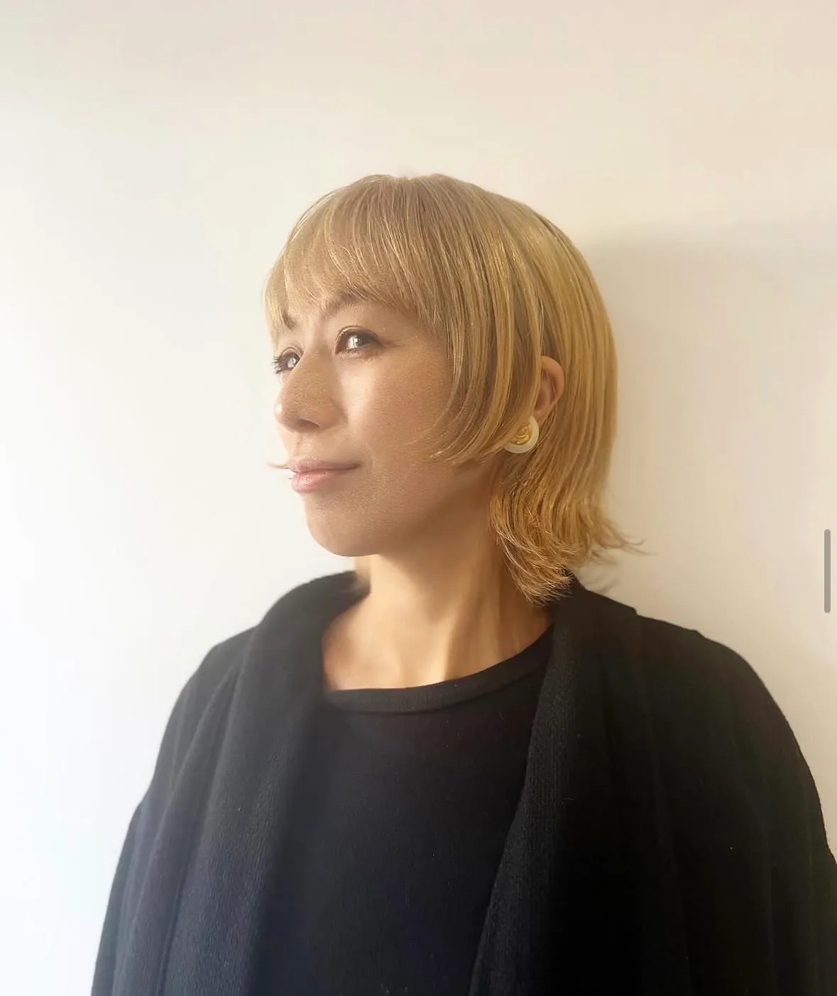 耳まわりを軽くした、ブロンドのウルフボブの女性の横顔