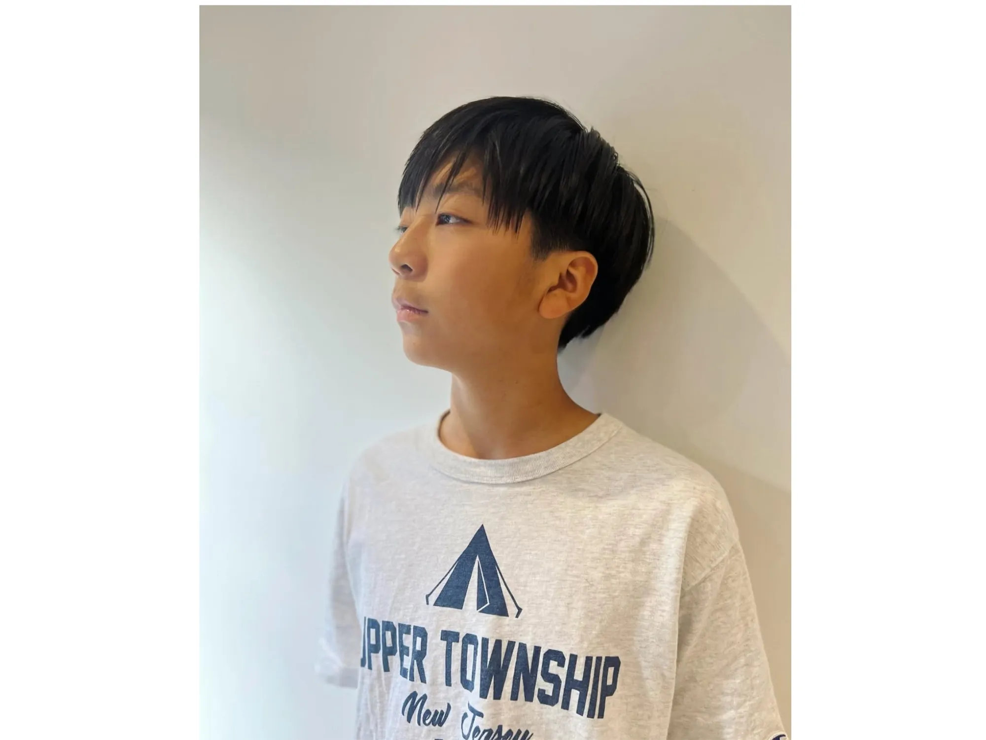 壁に寄りかかる、刈り上げがすっきりした男の子の横顔