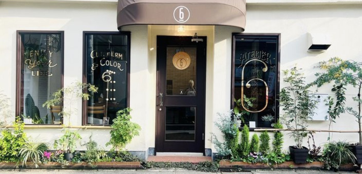 《エリア名》にある美容室Atelier 6の店舗外観。緑の植物に囲まれた入り口。