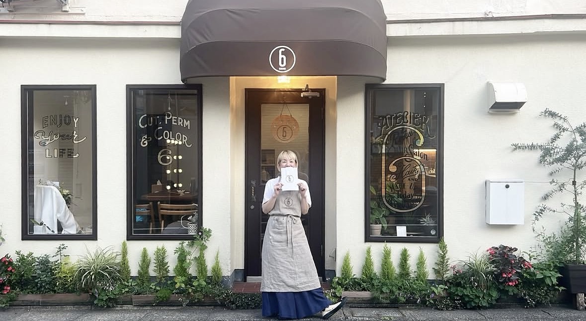 《エリア名》の美容室Atelier 6のオーナースタイリストが店舗前に立つ様子